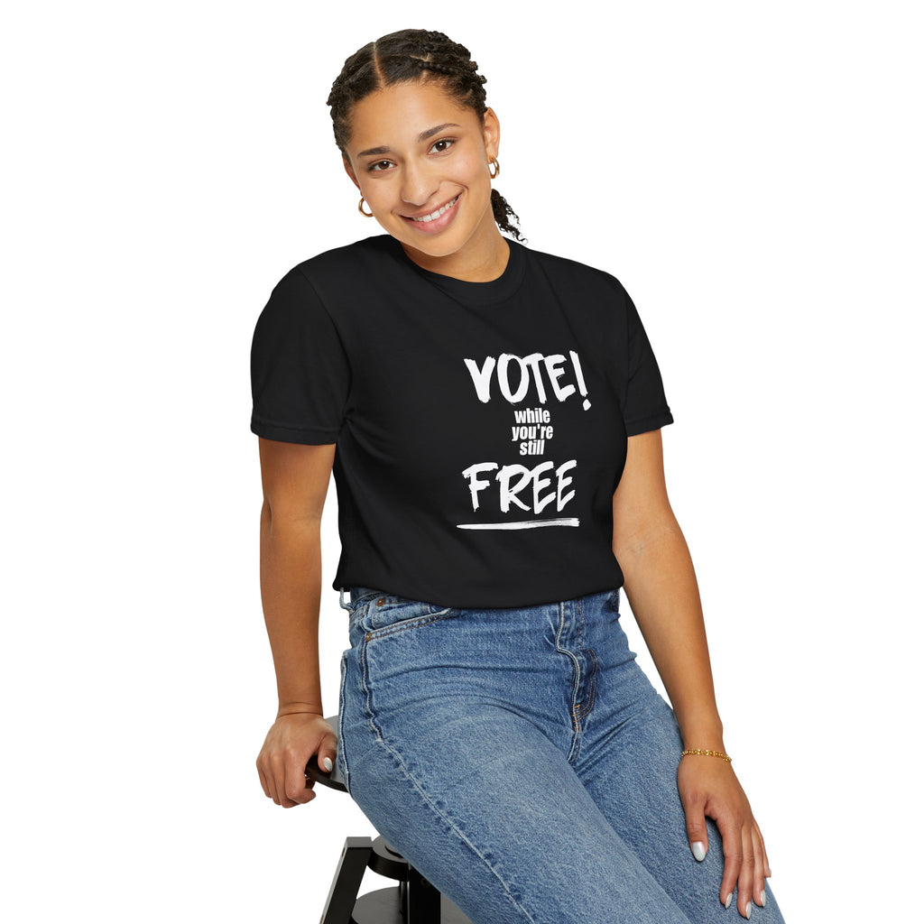 Person wearing a black t-shirt with 'Vote! While You're Still  free' text on a white background
